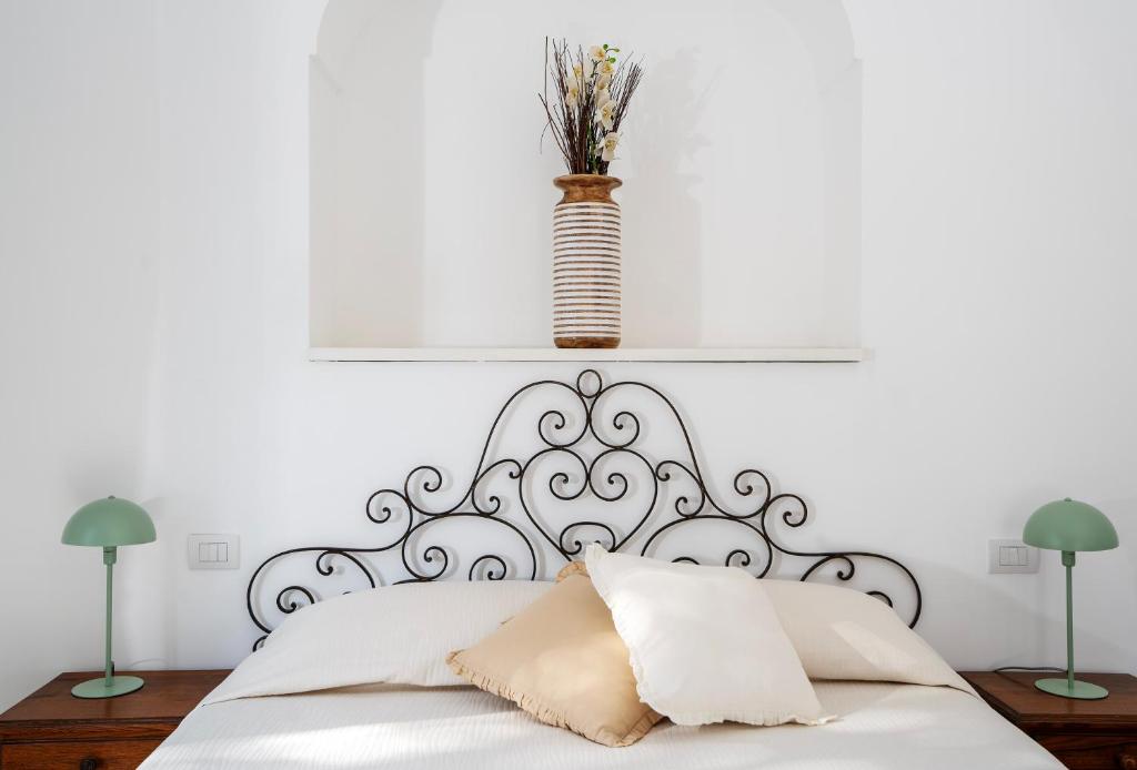 een witte slaapkamer met een wit bed met een vaas erop bij Villa Pineta - Holiday House in Anacapri