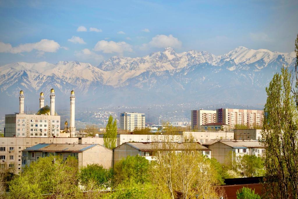a city with buildings and mountains in the background at Новая квартира с панорамным видом на горы in Almaty
