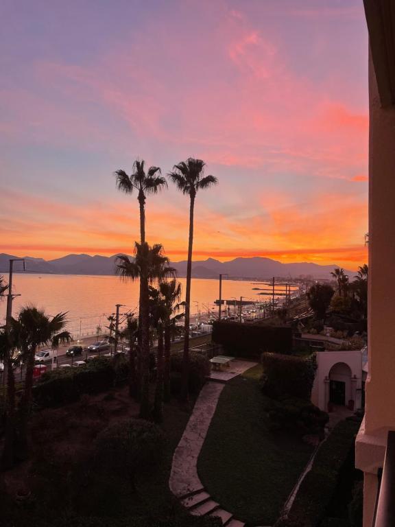 un coucher de soleil sur l'eau avec des palmiers dans l'établissement Résidence Palme d'Azur Cannes La Bocca, à Cannes