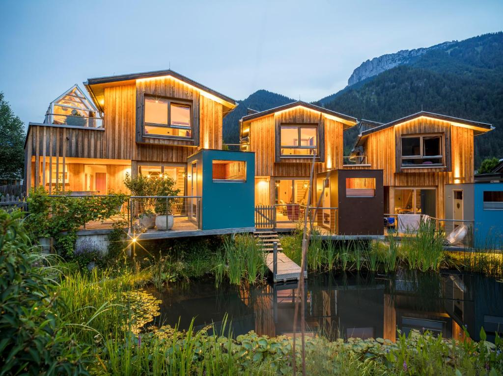 een houten huis met een rivier ervoor bij Alpegg Chalets in Waidring