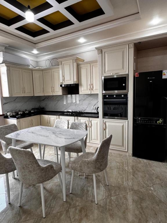 uma cozinha com mesa, cadeiras e electrodomésticos em Квартира Самарканд em Samarcanda