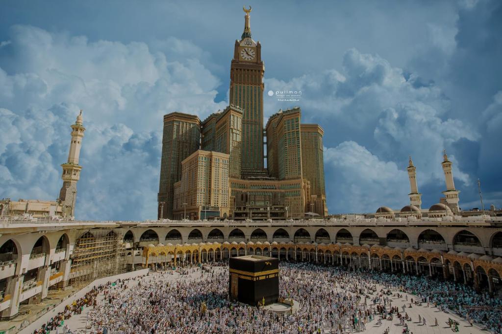 una grande folla di persone in una città con una torre dell'orologio di Pullman ZamZam Makkah a La Mecca