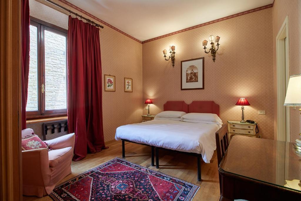a bedroom with a bed and a chair and a window at Hotel Hermitage in Florence