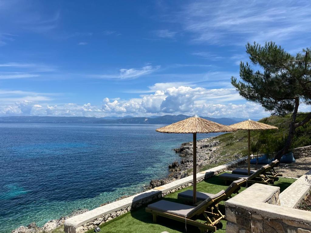 a beach with chairs and umbrellas and the ocean at Paxos Sunrise Villas in Gaios