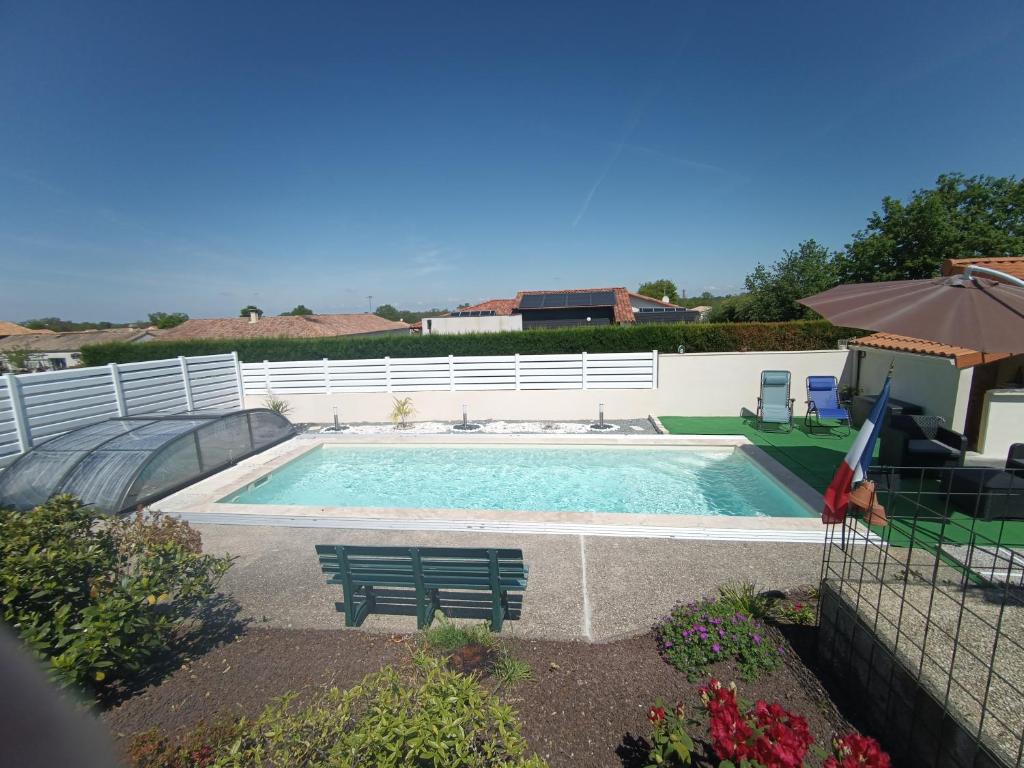 a swimming pool with a bench and an umbrella at Le Studio in Saint-Martin-des-Tilleuls