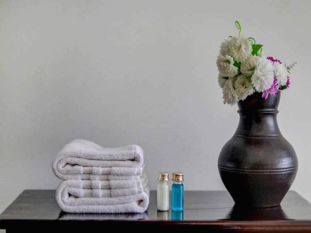 einen Tisch mit einem Handtuch und eine Vase mit Blumen in der Unterkunft Collection O 93572 HOTEL EXECUTIVE INN in Silchar