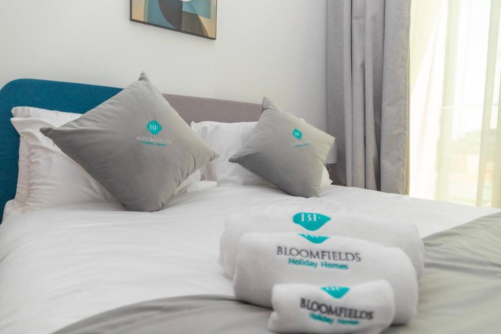 Bloomfields -1br Oasis 2 في أبوظبي: سرير أبيض مع وسائد عليه علامات طبية عليه