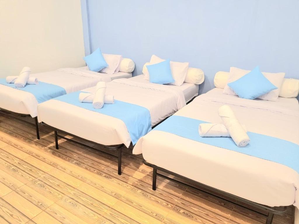 fila de camas con almohadas azules y blancas en Zizi Homey Cemara Asri Triple Room 202, en Medan