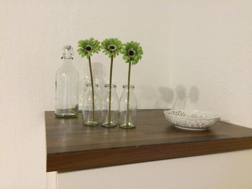 a shelf with four glass bottles and flowers on it at Ferienwohnung Am Flörbach in Ahaus