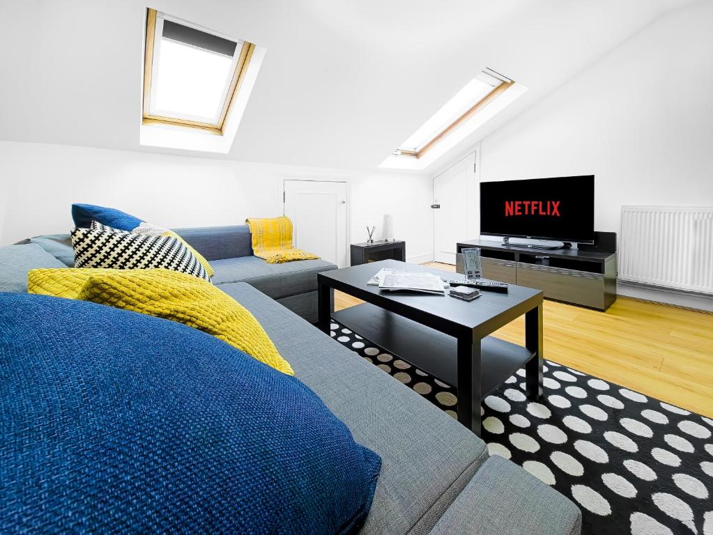 ein Wohnzimmer mit einem Sofa und einem TV in der Unterkunft Charming London Home, Opp Arnos Grove Underground Station in New Southgate