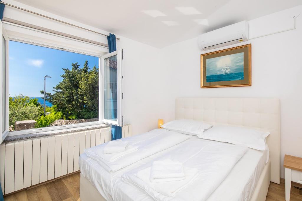 een slaapkamer met een wit bed en een groot raam bij Apartments Soul in Krk