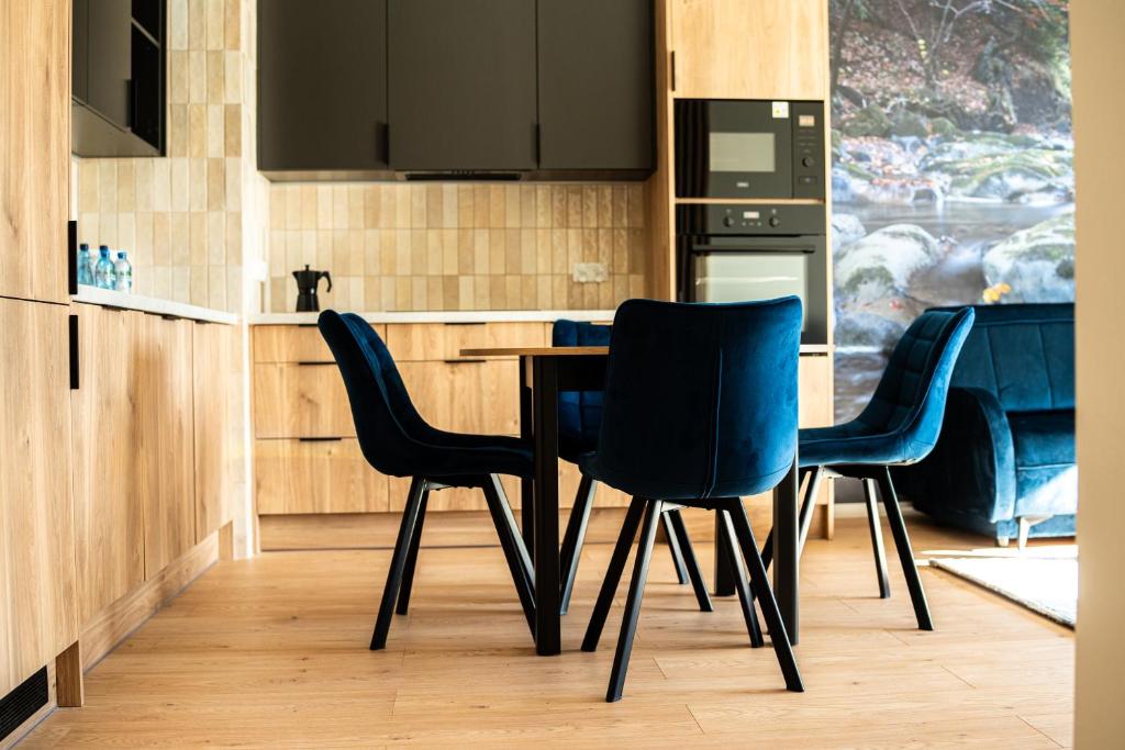 a kitchen with three chairs and a wooden table at Apartamenty Lesko 36 in Lesko