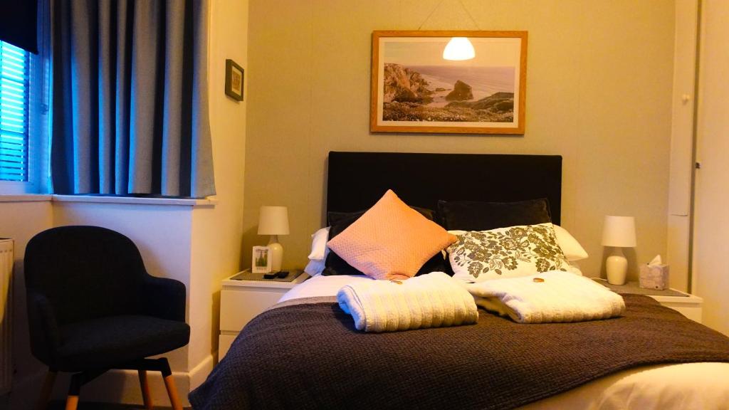 a bedroom with a bed with pillows and a chair at Cliftonville, en-suite room, fridge microwave TV, great value homestay near the sea in Lymington