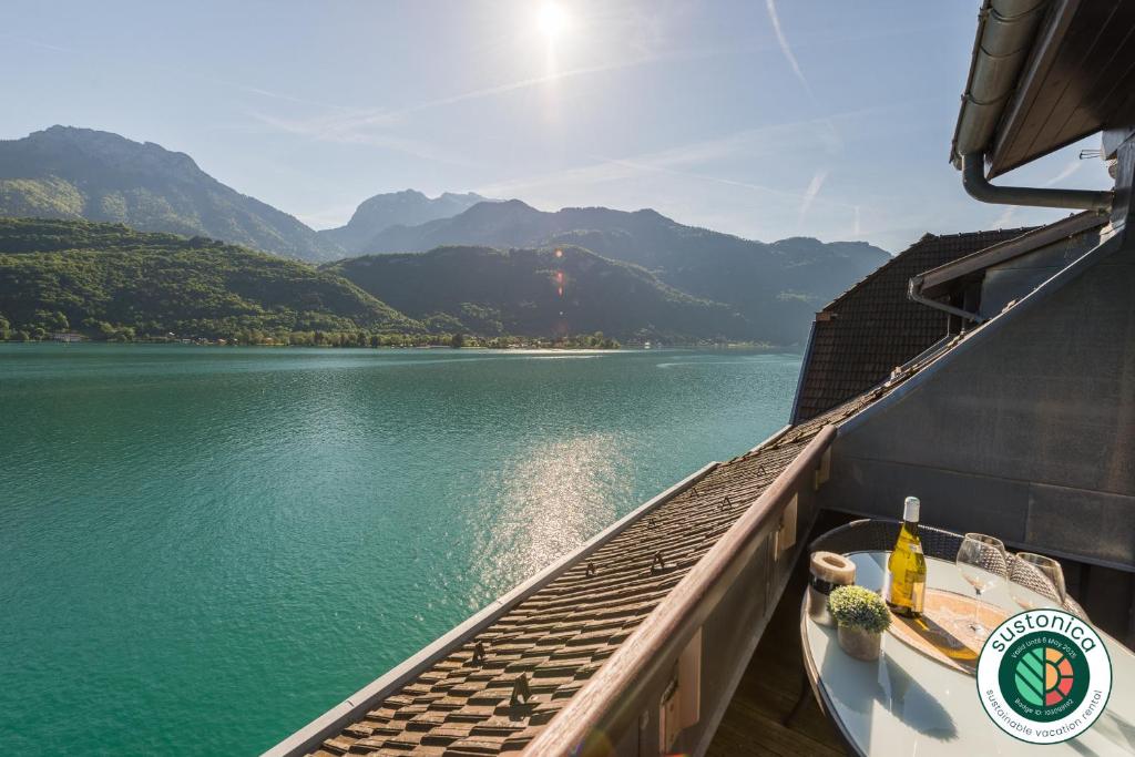 a boat on a lake with mountains in the background at Les Libellules accès direct au lac, 7 apts du studio au 4 ch, LLA Selections by LocationlacAnnecy in Duingt