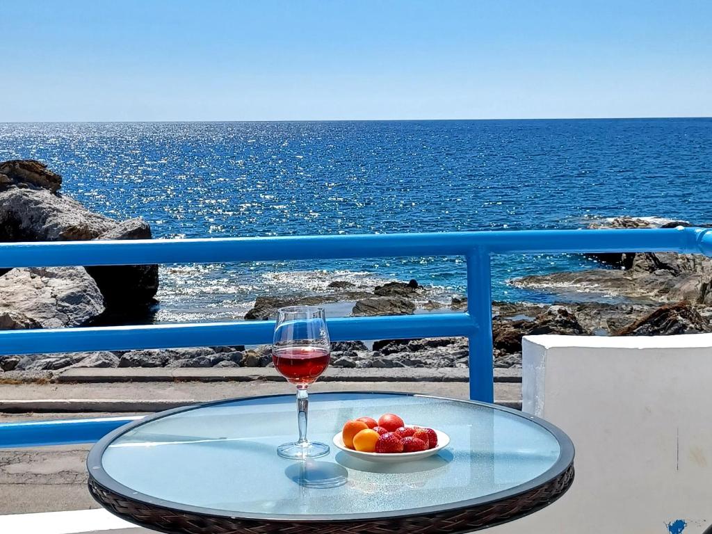 - un verre de vin sur une table avec un bol de fruits dans l'établissement Haris Studios, à Paleóchora