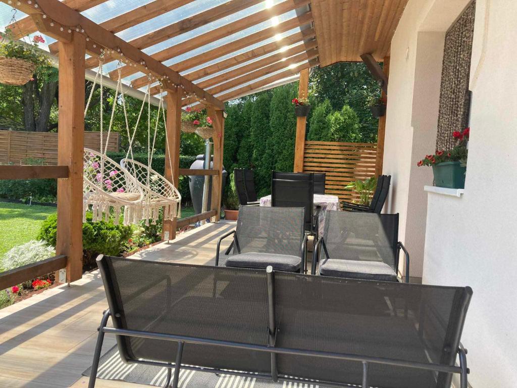 a patio with black chairs and a wooden pergola at Levendula Vendégház in Balatonföldvár