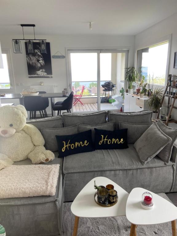 a teddy bear sitting on a couch in a living room at L’élégance au bord du Lac in Évian-les-Bains