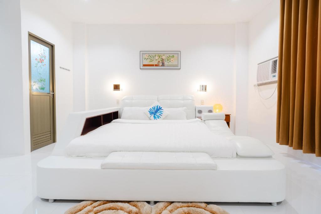 a white bedroom with two white beds in it at Q Beach Resort in Cabangan