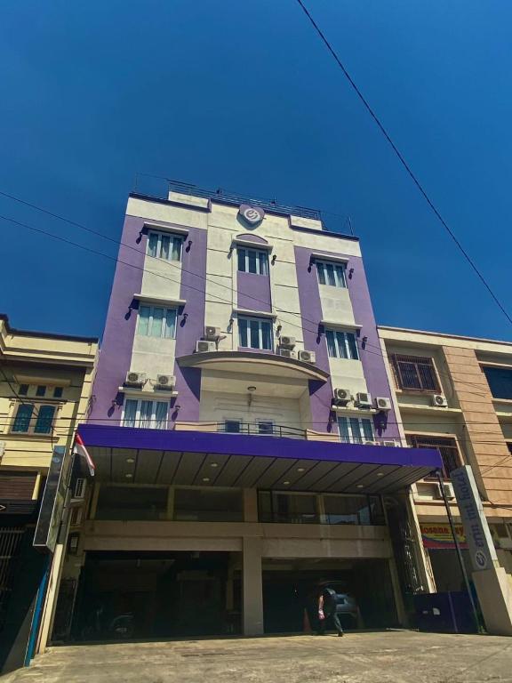 un edificio alto púrpura con un reloj en él en Erin Int Hotel en Sungguminasa