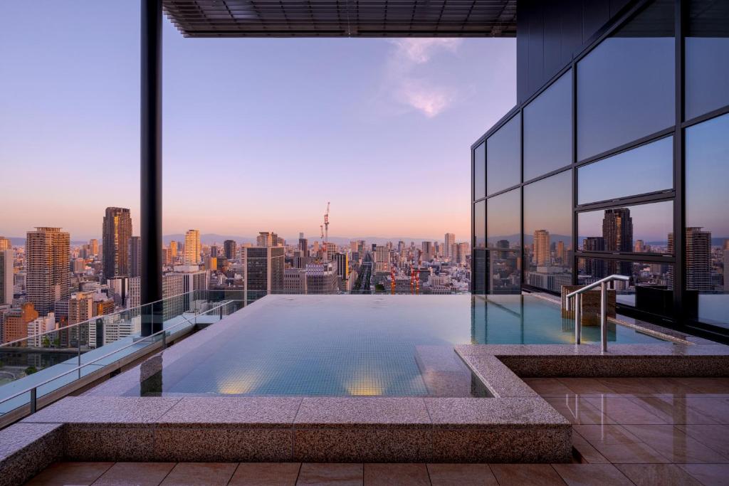 a swimming pool on the roof of a building with a city at Candeo Hotels Osaka The Tower in Osaka