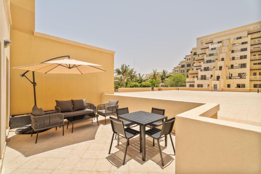 a patio with a table and chairs and an umbrella at Nasma Luxury Stays - Luxurious Coastal Living Bab Al Bahr Residences in Ras al Khaimah
