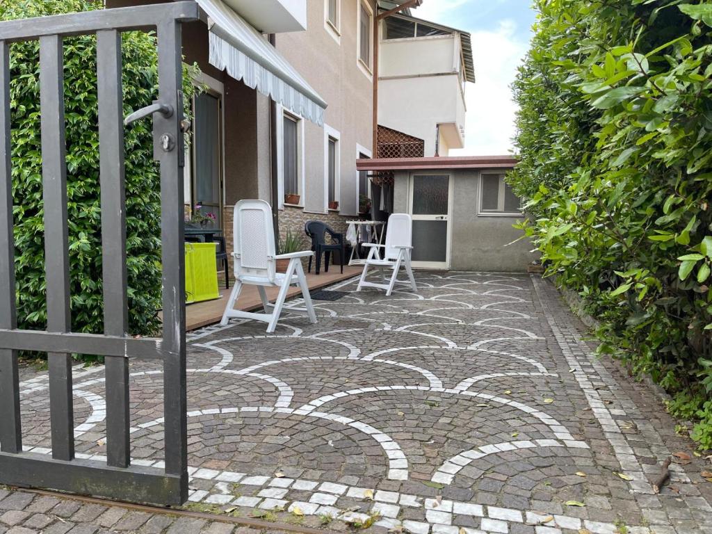 un patio con sillas blancas y una valla en La casa di Morena, en Torre del Lago Puccini