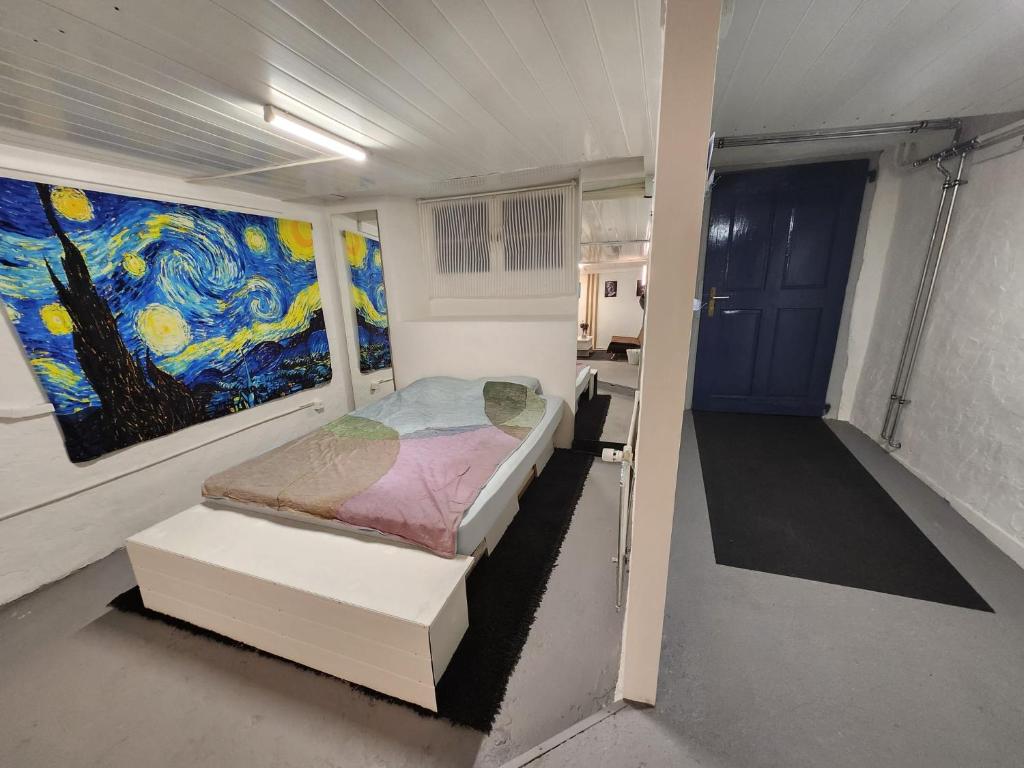 Schwändi的住宿－Spacious cellar studio surrounded by mountains and lake，卧室配有一张床,墙上挂有绘画作品