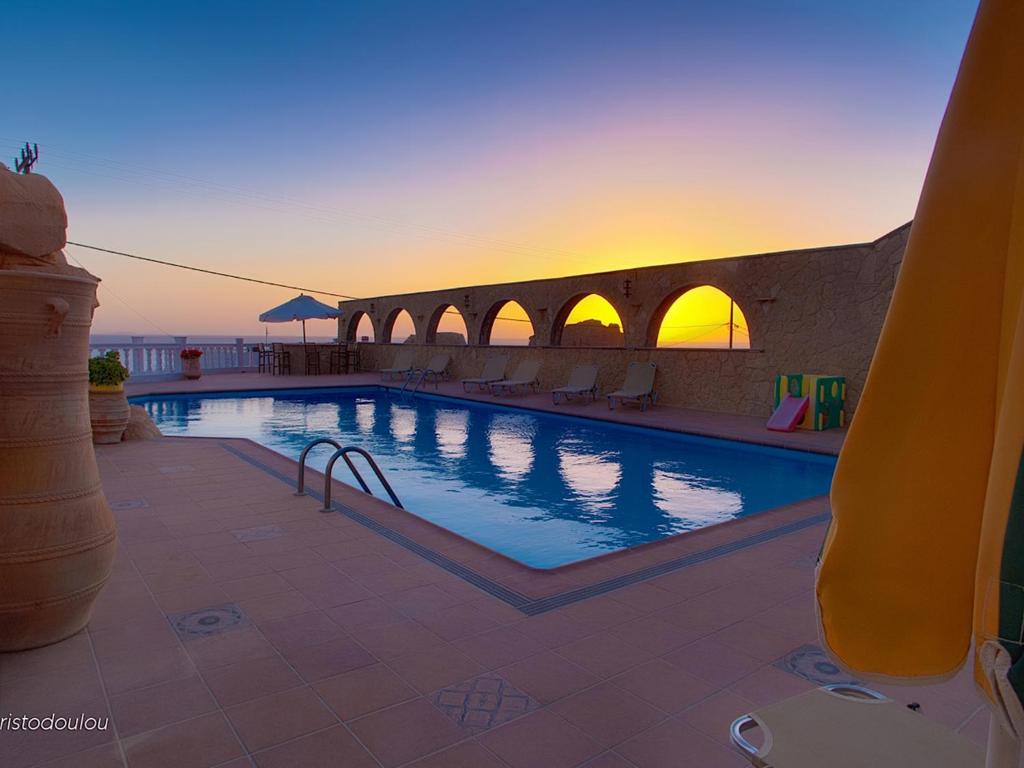 a swimming pool with a sunset in the background at Hotel Finiki View in Foiníkion