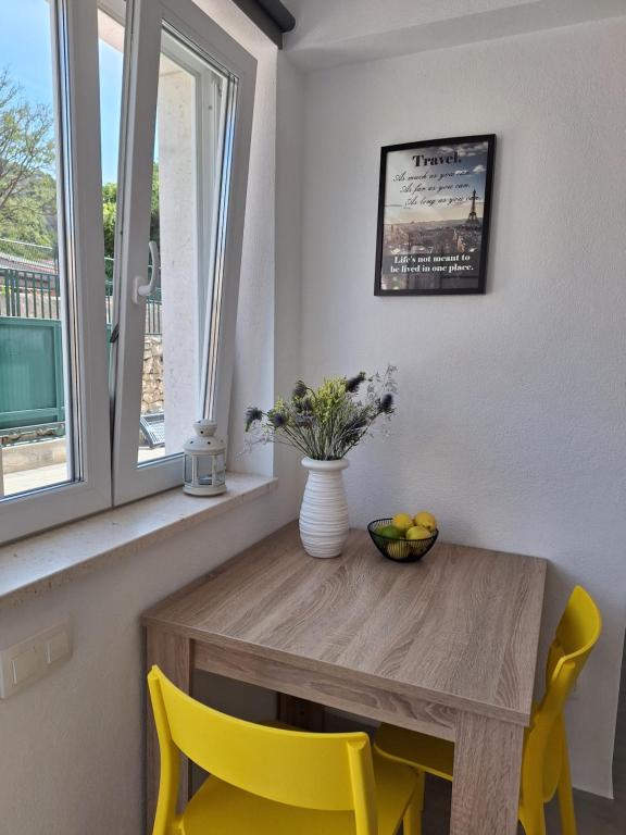 une table à manger avec des chaises jaunes et un vase de fleurs dans l'établissement Mimi, à Hvar