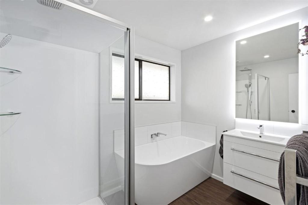 een witte badkamer met een bad en een wastafel bij Spacious Room Near Christchurch Airport in Christchurch
