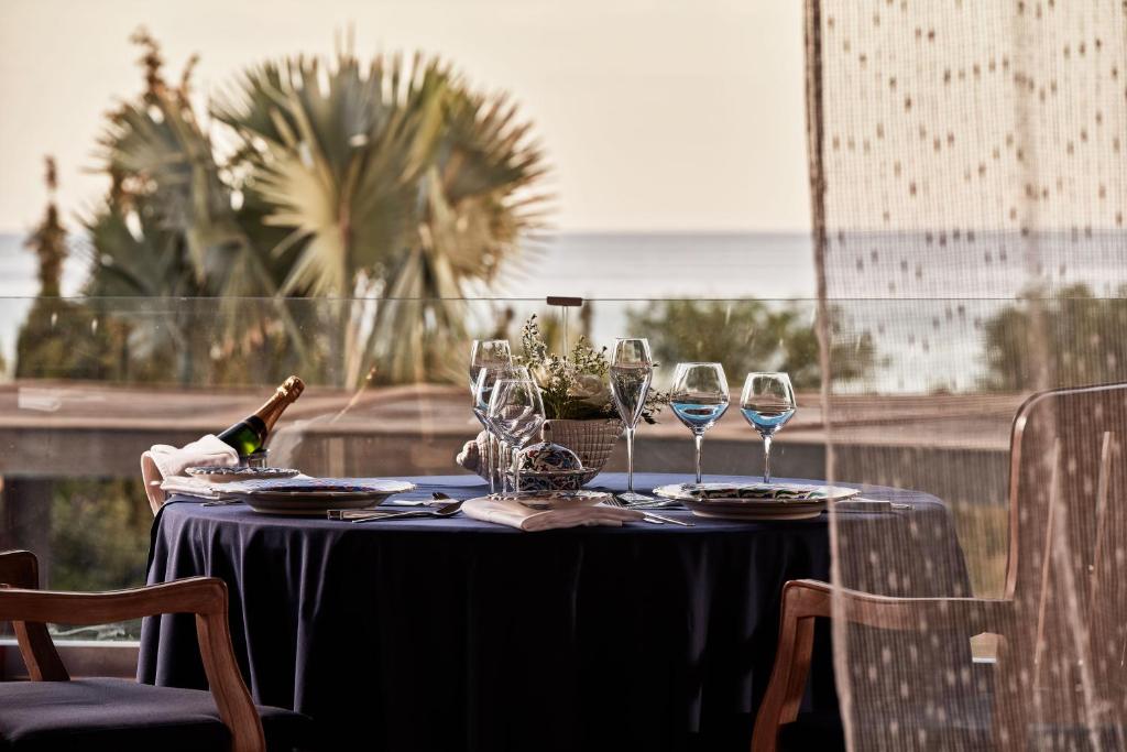 a table with glasses and a bottle of wine on it at Aquagrand Exclusive Deluxe Resort Lindos - Adults only in Lindos
