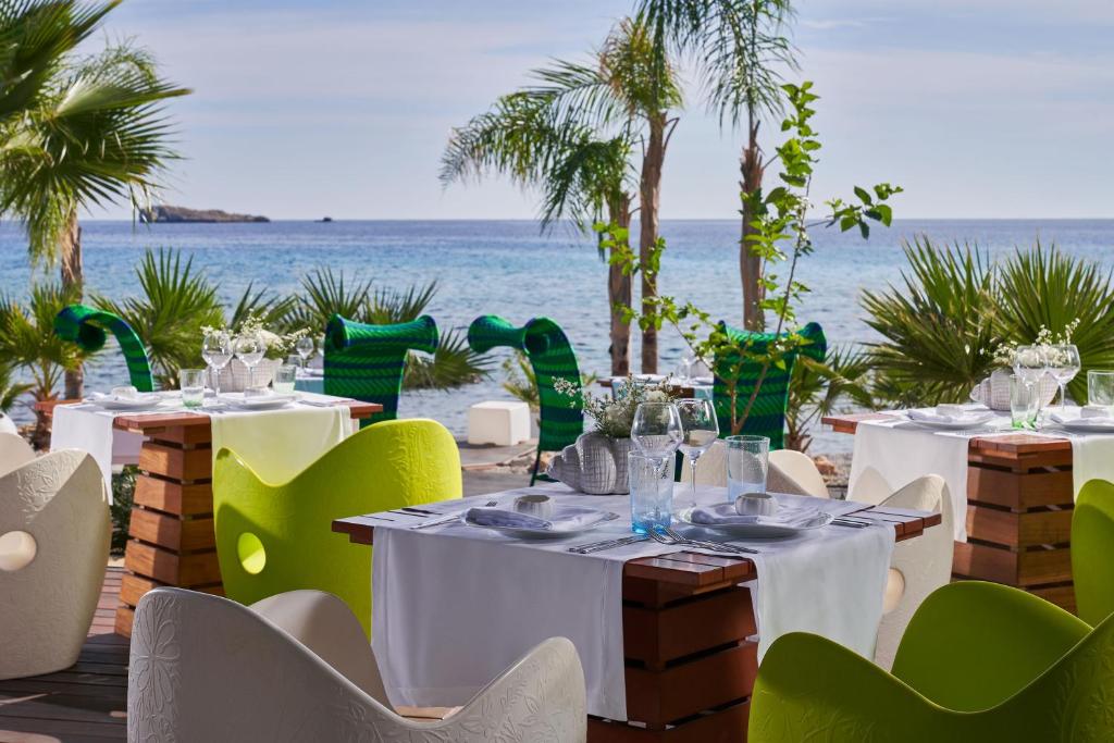 a restaurant with white tables and chairs and the ocean at Aquagrand Exclusive Deluxe Resort Lindos - Adults only in Lindos
