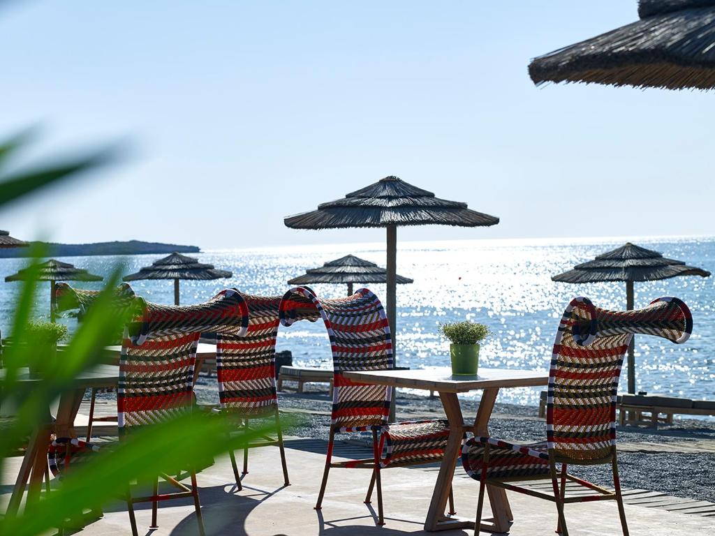a group of chairs and a table with umbrellas on the beach at Aquagrand Exclusive Deluxe Resort Lindos - Adults only in Lindos