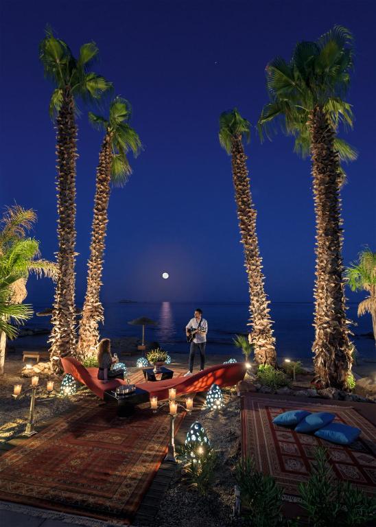 a group of people sitting on a beach with palm trees at Aquagrand Exclusive Deluxe Resort Lindos - Adults only in Lindos
