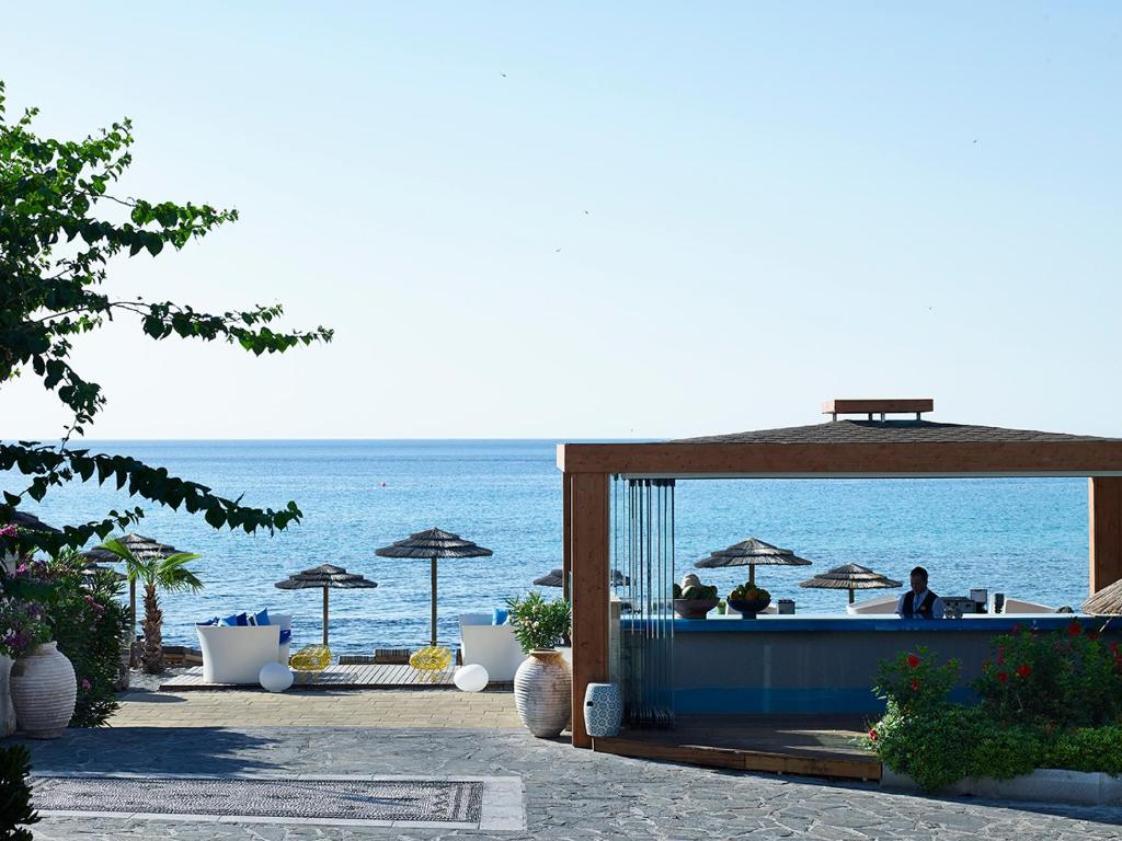 a bar on the beach with the ocean in the background at Aquagrand Exclusive Deluxe Resort Lindos - Adults only in Lindos