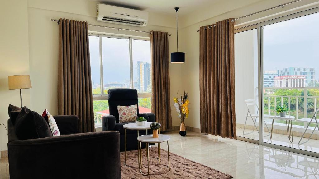 ein Wohnzimmer mit einem Sofa und Stühlen sowie einem großen Fenster in der Unterkunft Olive Service Apartments New Town in Kalkutta