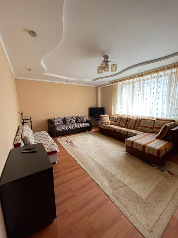 een grote woonkamer met banken en een televisie bij ЖК «Нурсая» in Astana