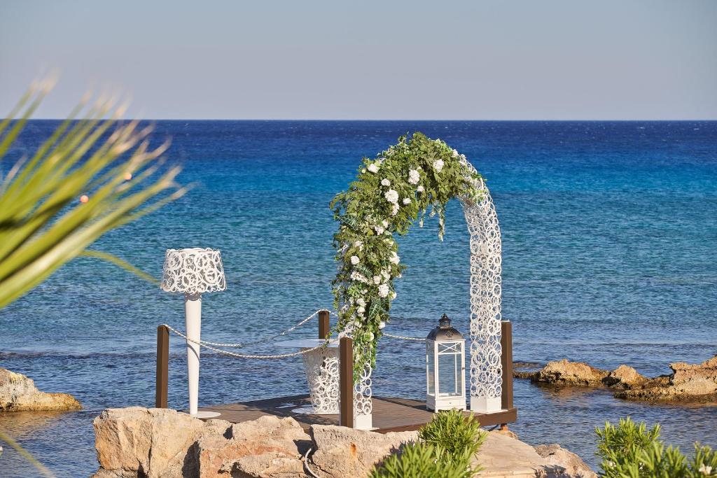 a wedding arch on the beach next to the water at Aquagrand Exclusive Deluxe Resort Lindos - Adults only in Lindos