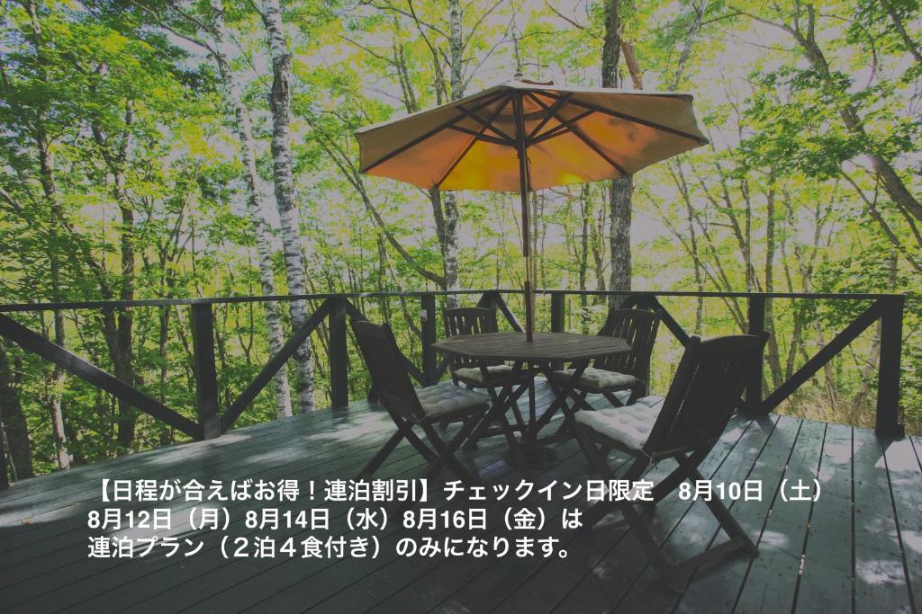 a table and chairs under an umbrella on a deck at Guesthouse Kreutzer in Chino