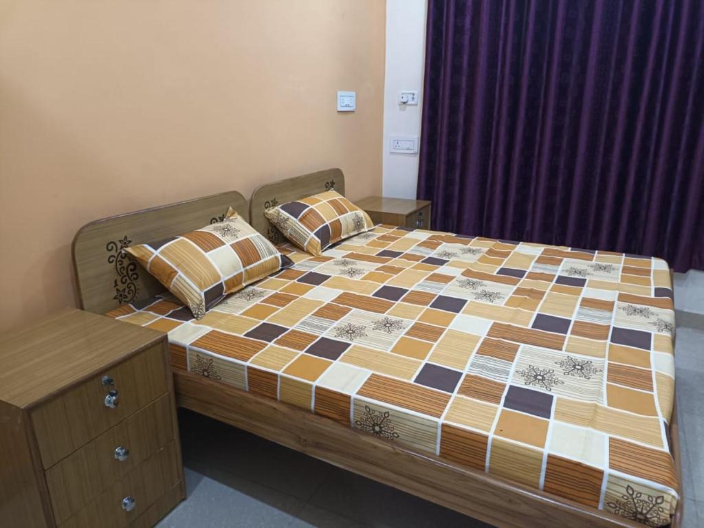 ein Schlafzimmer mit einem Bett mit einer karierten Bettdecke in der Unterkunft Anant Paying Guest house in Ayodhya