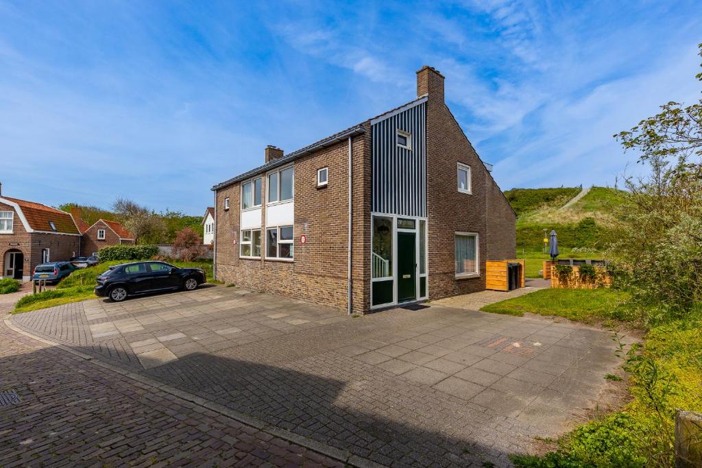 uma casa de tijolos com um carro estacionado em frente em Hogehilweg 16 vakantiehuis, Direct onder de duinen - eigen parkeerplaatsen em Domburg