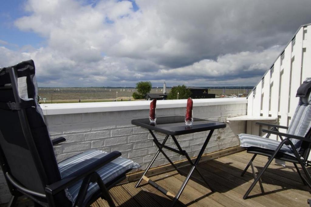 d'un balcon avec deux chaises et une table sur le toit. dans l'établissement Lüttke Juwel, Ferienwohnung mit traumhaftem Seeblick, à Lembruch