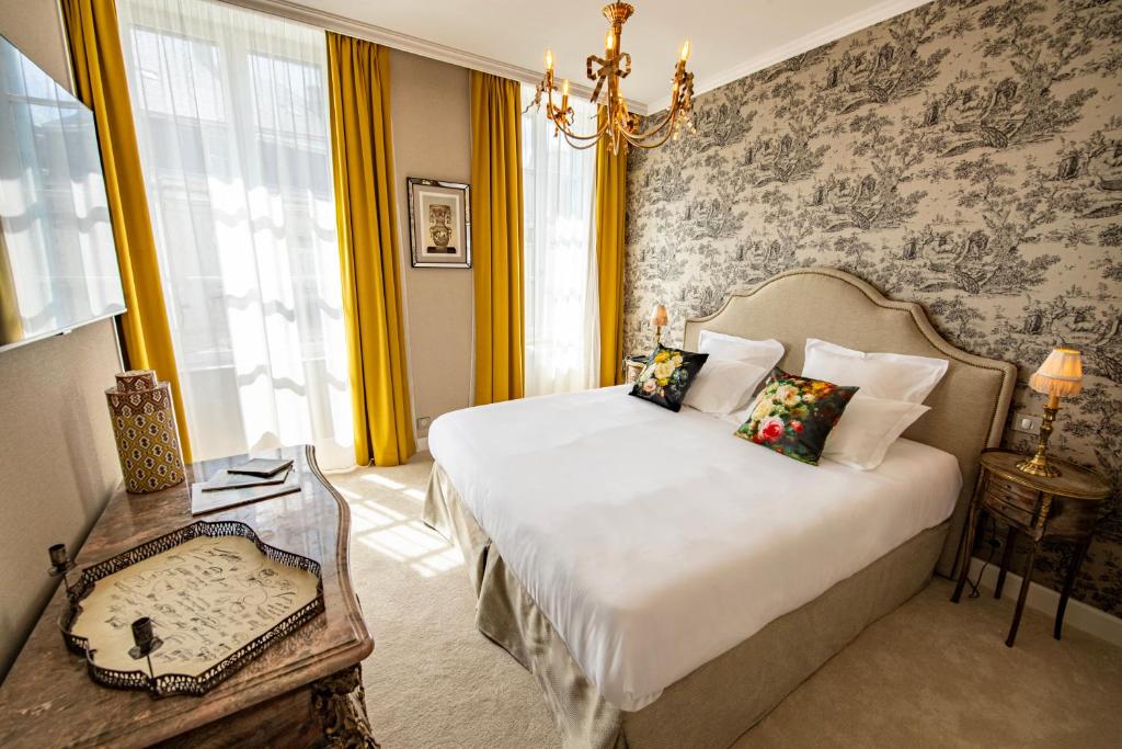 sypialnia z łóżkiem i żyrandolem w obiekcie Hôtel de la Poste w mieście Avallon