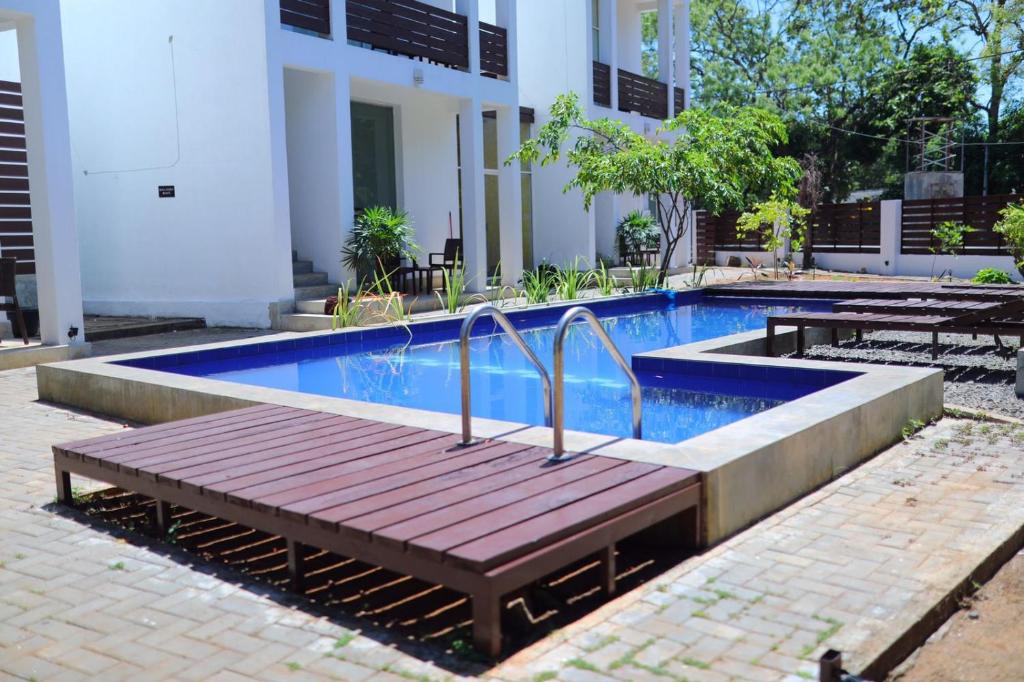um banco de madeira ao lado de uma piscina em Ananthara Resort em Anuradhapura