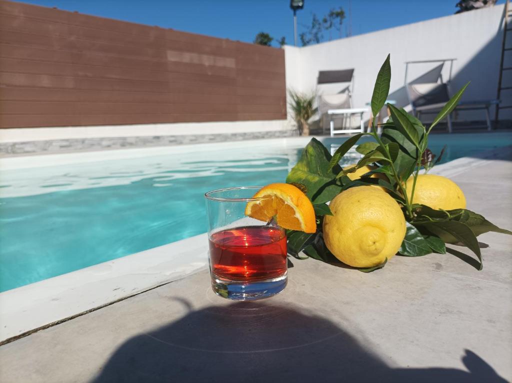 a glass of juice and lemons next to a pool at tropical loft in Salemi