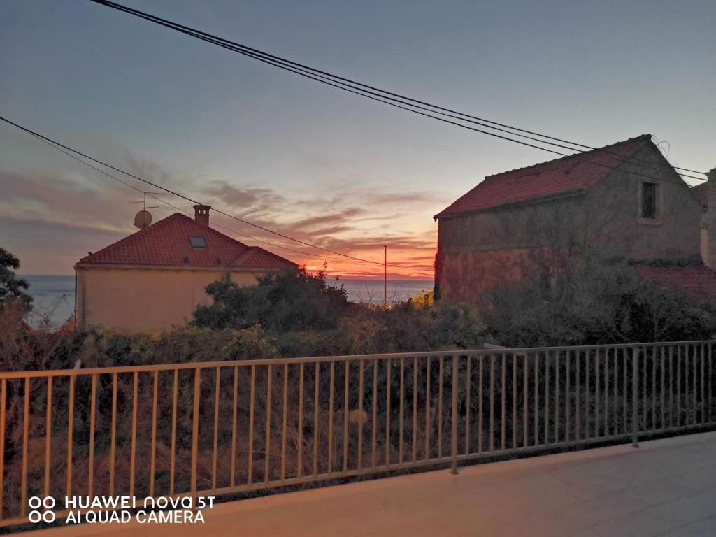 a sunset behind two buildings and a fence at Apartments Palma Ragusa in Dubrovnik