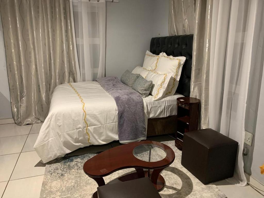 Dormitorio pequeño con cama y mesa en Self-Catering Garden Flat in Hochlandpark - 5min from Widhdoek CBD, en Windhoek