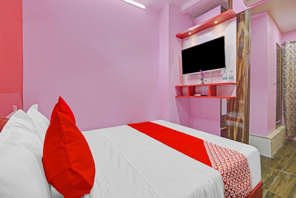 een slaapkamer met een bed met rode kussens en een televisie bij OYO Flagship Hotel Happiness Inn Near Tdi Mall in New Delhi