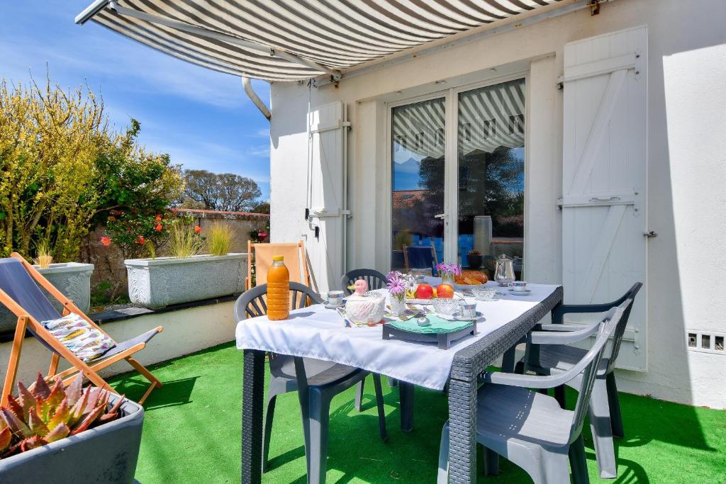 une table et des chaises sur une terrasse avec de l'herbe verte dans l'établissement Échappée à 400m de la plage des Sableaux, à Noirmoutier-en-l'lle