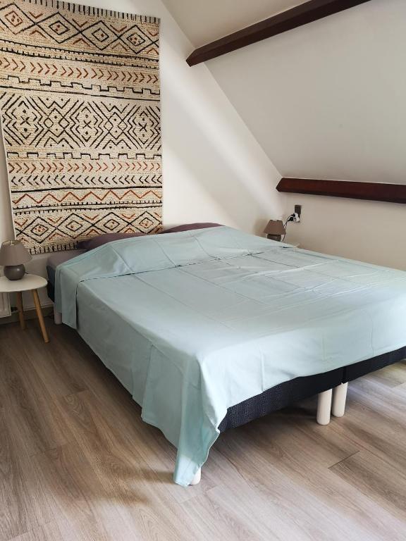 une chambre avec un grand lit avec un couvre-lit bleu dans l'établissement Le Moment Normand, à Émalleville